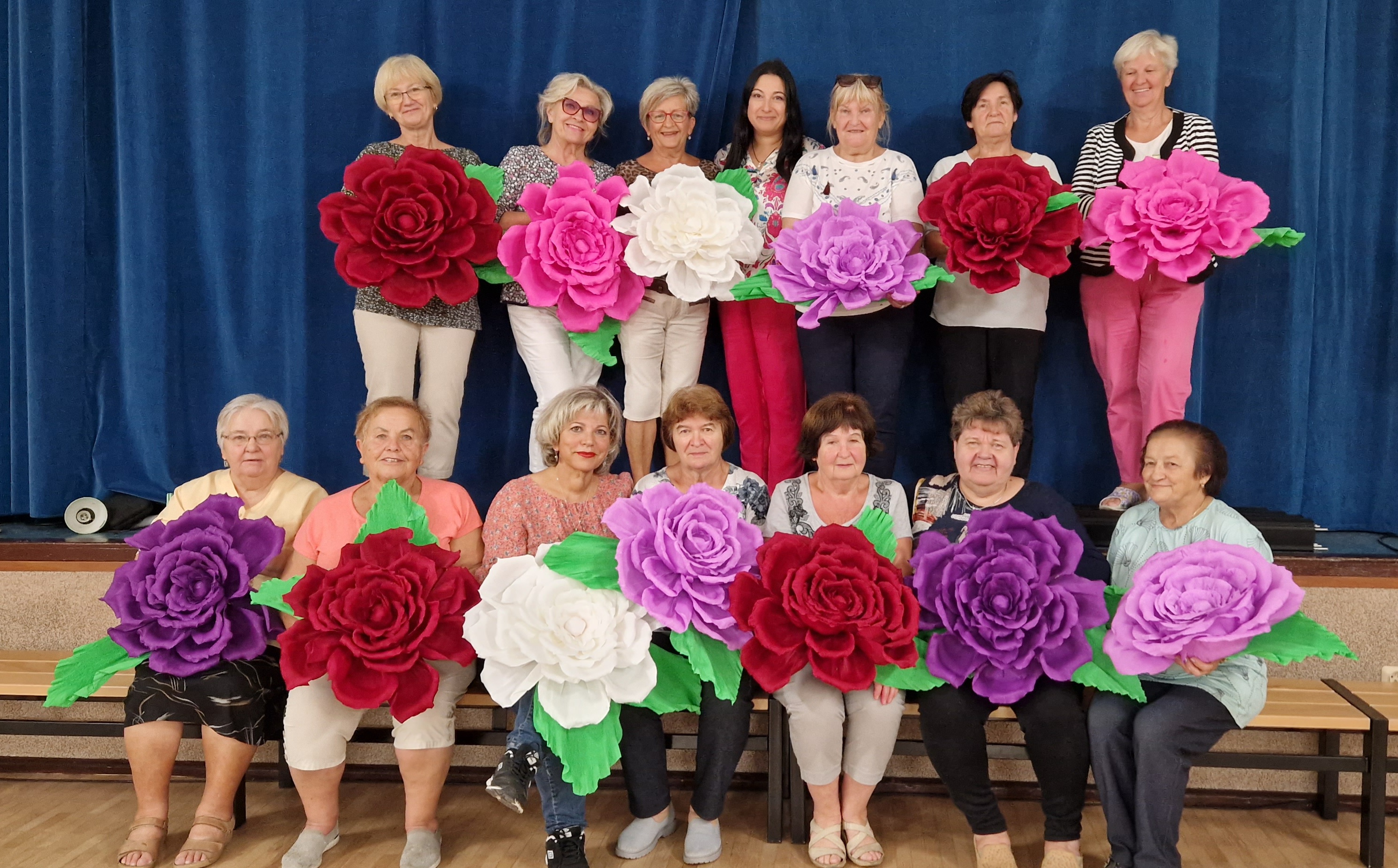 a group of ladies holding large paper flowers