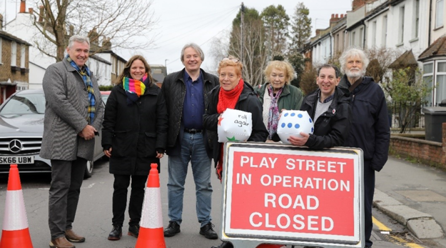 a group of people next to the play streets sign