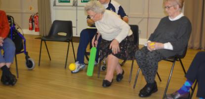 Seated group of people hitting a ball with a cricket bat